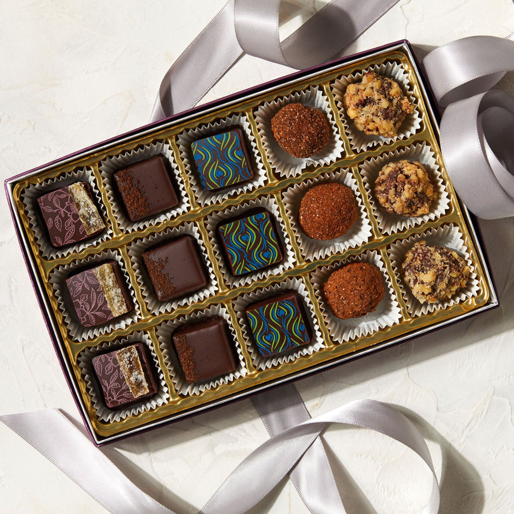 Assorted chocolates in a decorative box with white ribbons on a light background